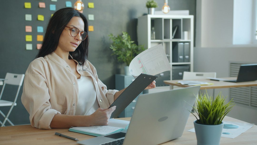 Business owner reviewing a document beside a laptop before choosing the right level of business assessment